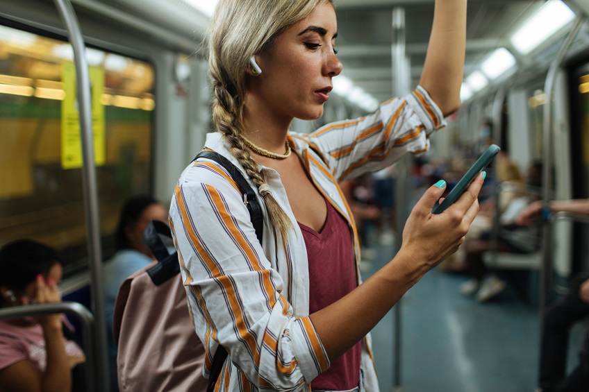 Femme dans le métro qui regarde son téléphone