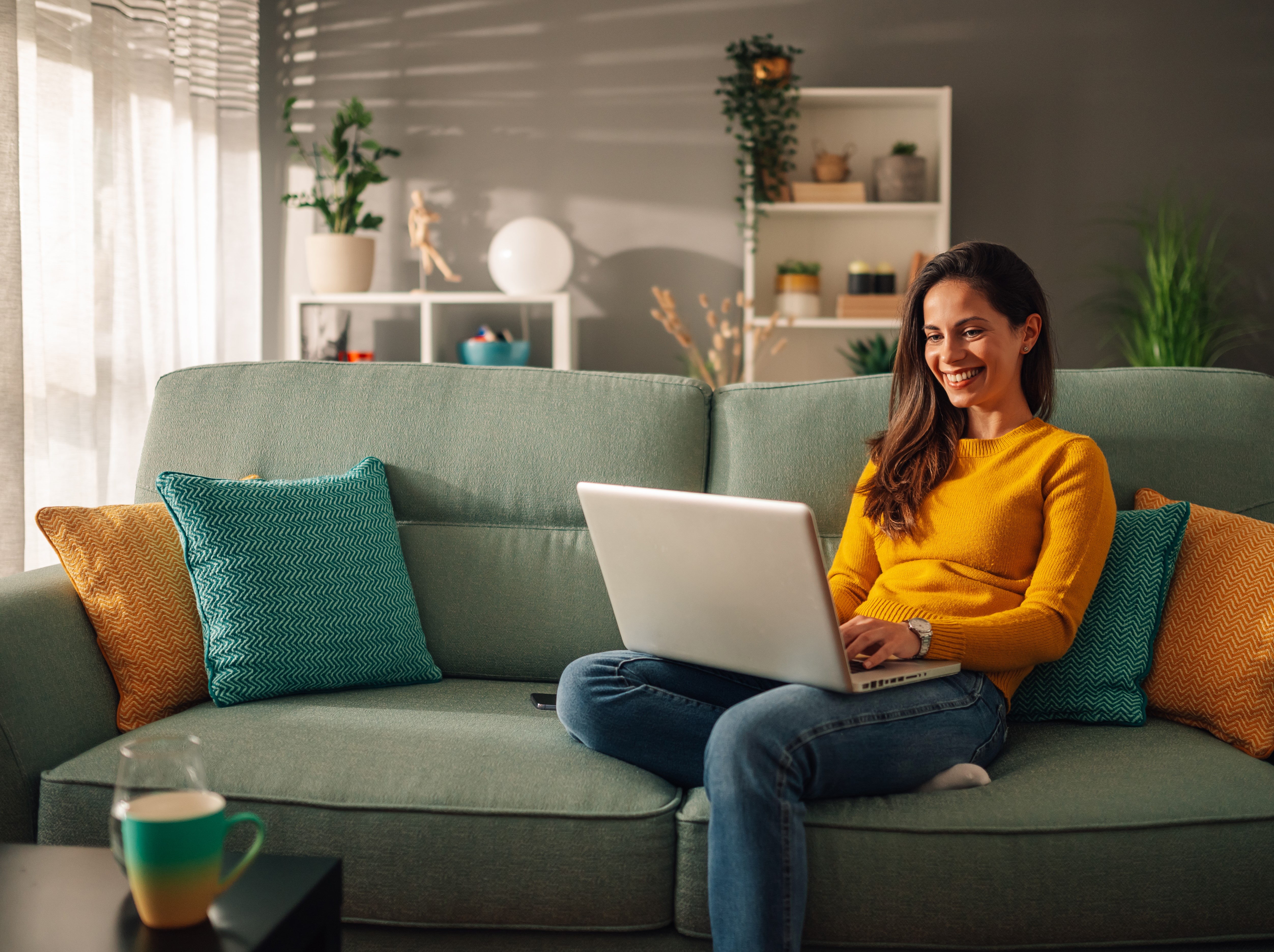 Frau sitzt auf einem Sofa und benutzt einen Computer